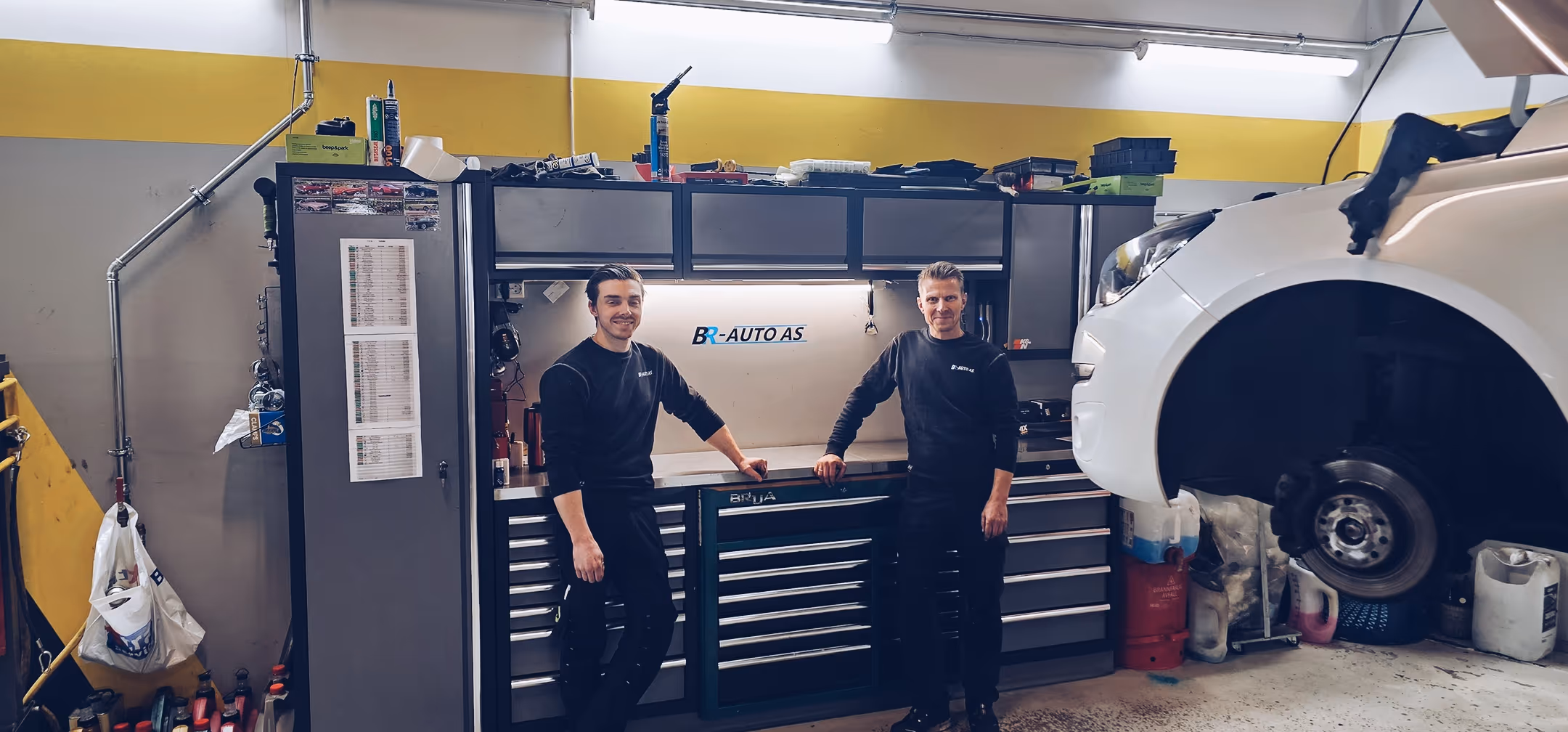 Einar og Mads Bru ved verktøybenken under BR-Auto-skiltet i verkstedet i Stavanger.