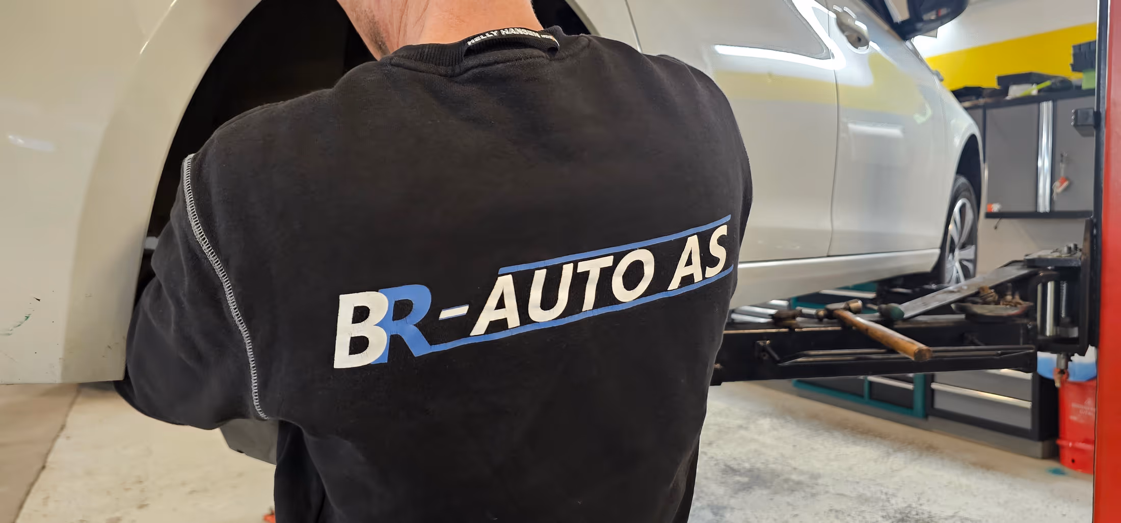 Mekaniker med BR-Auto-arbeidsklær ved en bil på hjulstillingsbenk i verkstedet i Stavanger.